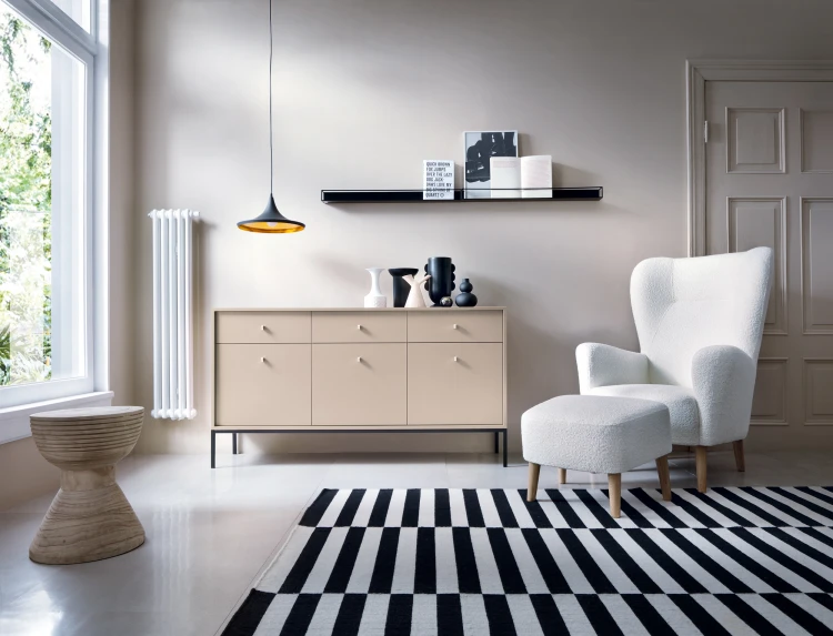 Komoda Mono 154 cm ustawiona przy ścianie w kolorze taupe, nastrojowe oświetlenie podkreślające kolor beż piaskowy