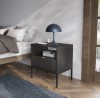Szafka nocna czarna Nova S54 przy łóżku w sypialni, lampka nocna na blacie, nowoczesny design i robot sprzątający