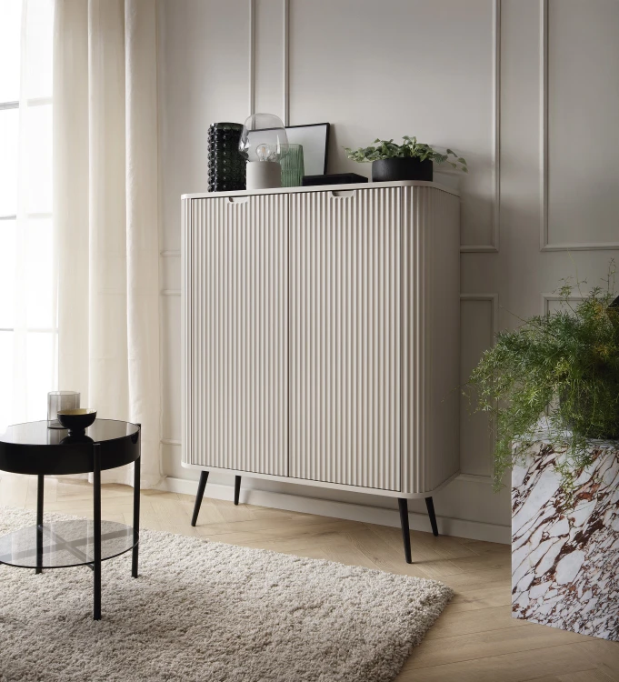 Wysoka komoda Zova K103 kaszmir w nowoczesnej sypialni, styl modern nude z czarnymi nóżkami, minimalistyczny design