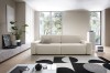 Beżowa sofa Bouli Raven 24 w nowoczesnym, przestronnym salonie jako główny punkt wypoczynkowy.