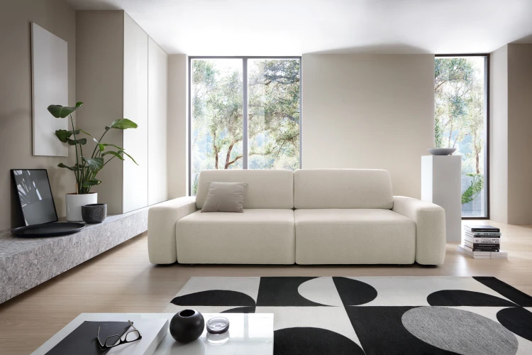 Beżowa sofa Bouli Raven 24 w nowoczesnym, przestronnym salonie jako główny punkt wypoczynkowy.