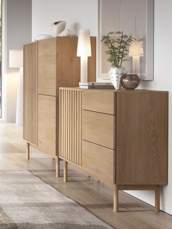 Elegancka aranżacja ściany w salonu, przy której stoją obok siebie dwie minimalistyczne komody z nowoczesnej serii Saori Cremona na wysokich drewnianych nóżkach.