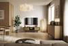 Elegancka szafka pod telewizor Deco RTV150 Baltic Dune zaaranżowana w nowoczesnym salonie z telewizorem wiszącym na ścianie i robotem sprzątającym przejeżdżającym pod meblem.