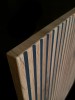 Zbliżenie na front 3D komody Sento, czarne pionowe lamele na tle dębu wotan, widoczna tekstura i głębokie ryflowanie